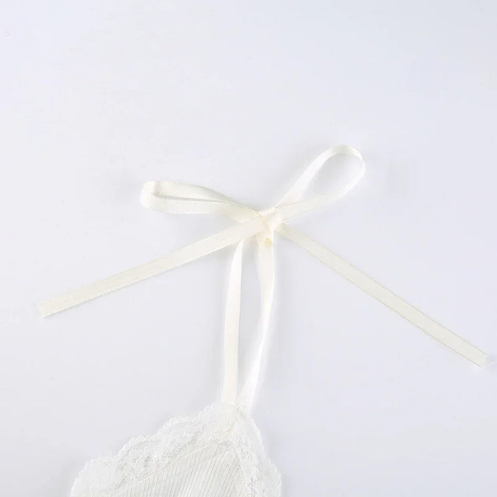 Cream white lace trim spaghetti strap with delicate ribbon bow detail on plain background