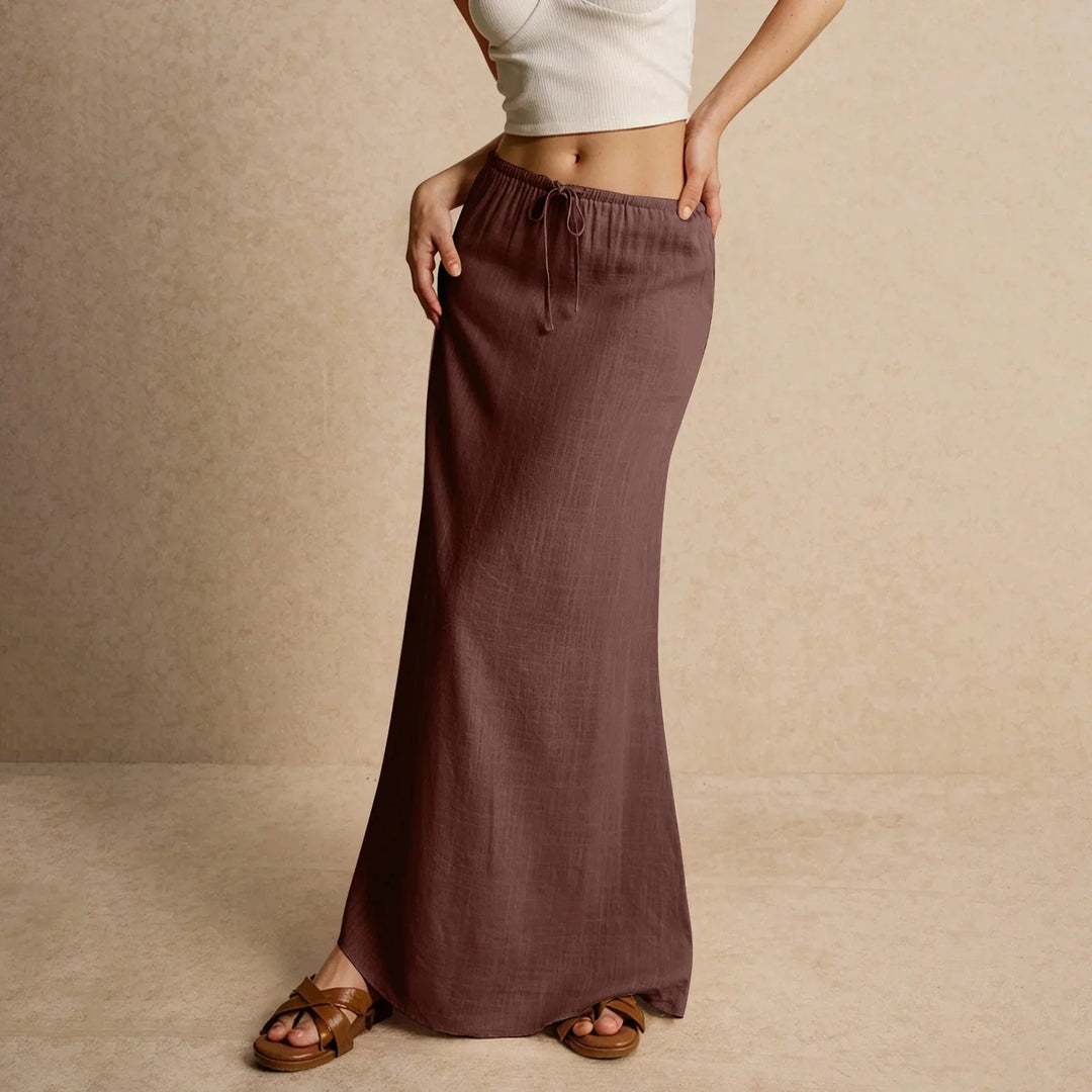 Woman wearing a mauve drawstring maxi skirt with brown sandals and a white cropped tank top