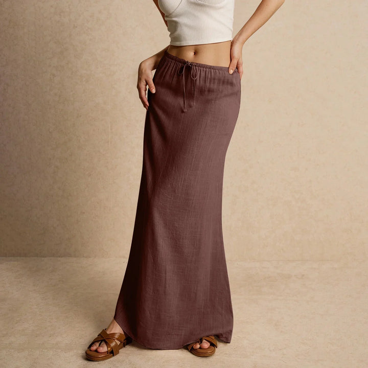 Woman wearing a mauve drawstring maxi skirt with brown sandals and a white cropped tank top