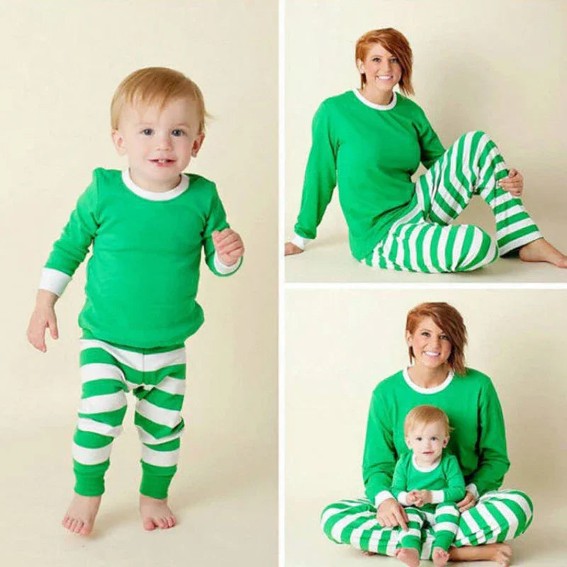 Mother and toddler in matching green and white striped Christmas pajamas posing against a cream background