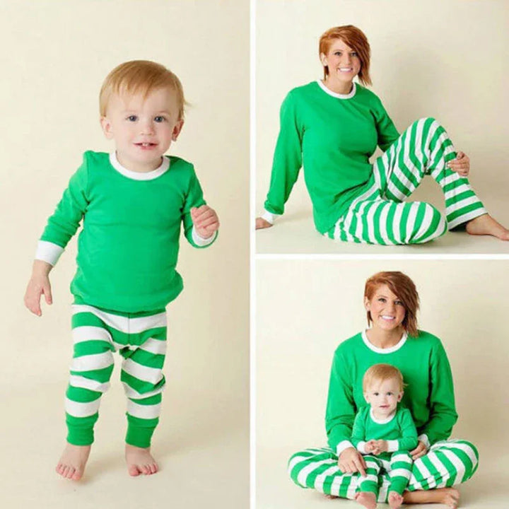 Mother and toddler in matching green and white striped Christmas pajamas posing against a cream background