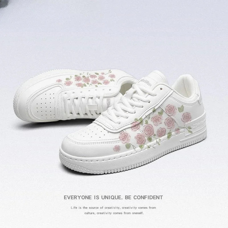 White casual sneakers with pink rose floral design and perforated toe box on plain background