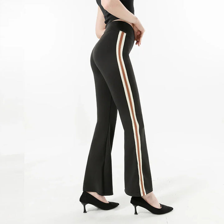 Side view of woman wearing black flare pants with brown and white side stripes and black heels