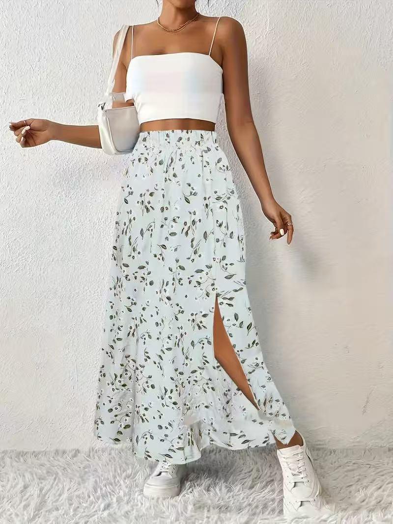 Woman wearing white crop top and floral high-slit maxi skirt with white sneakers and shoulder bag