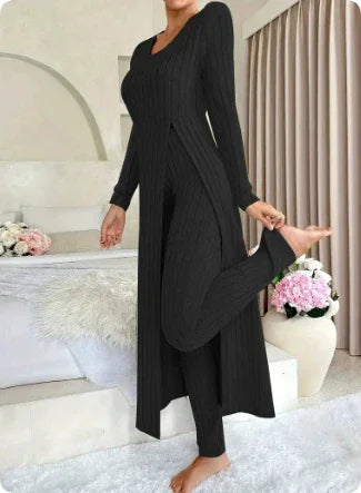 Woman wearing black ribbed long cardigan and leggings in stylish indoor setting with flowers