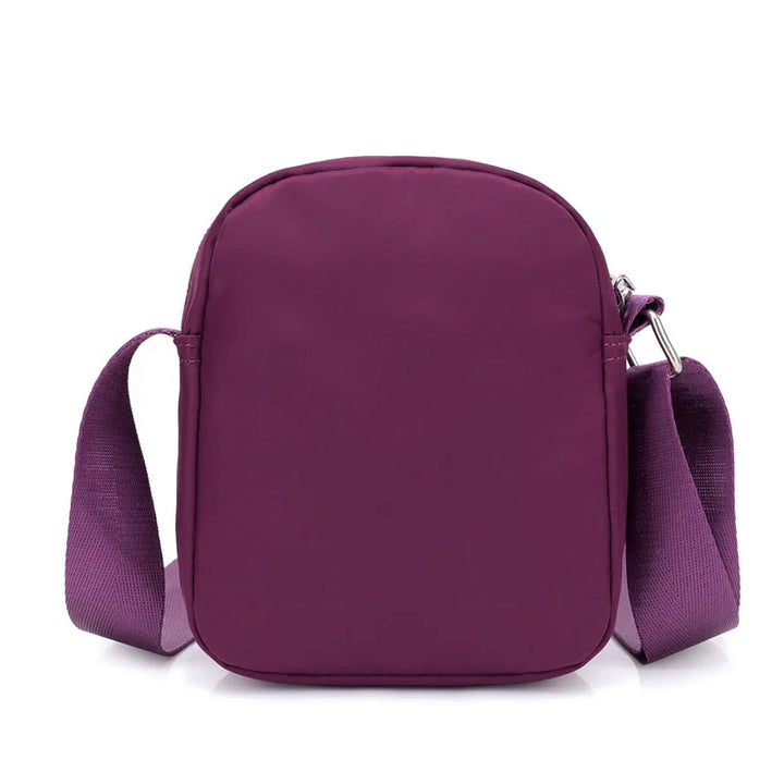 Compact purple crossbody bag with adjustable strap and silver buckle detail