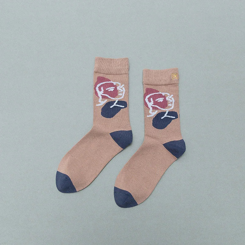 Pair of beige socks with blue heels and toes, featuring abstract face design in purple and white