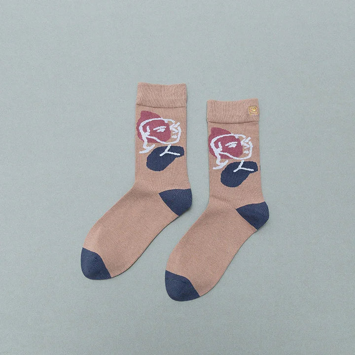 Pair of beige socks with blue heels and toes, featuring abstract face design in purple and white