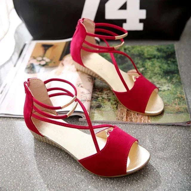 Pair of red open-toe wedge sandals with ankle straps displayed on a magazine background