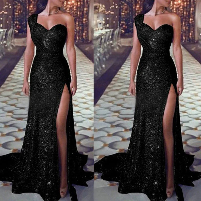 Elegant woman wearing a one-shoulder black sequin evening gown with thigh-high slit on a decorated runway