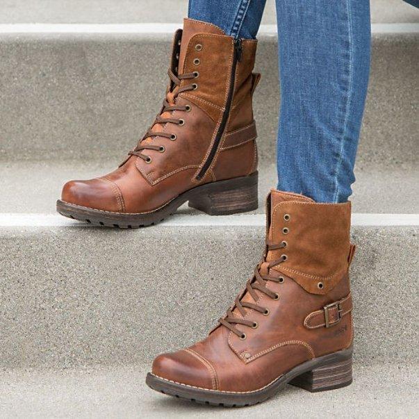 Brown leather lace-up ankle boots with side zippers and buckle detail worn with blue jeans on concrete steps