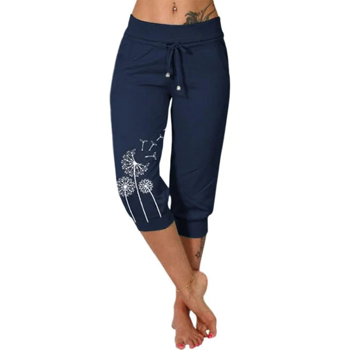 Woman wearing navy blue capri pants with white dandelion print, adjustable waist tie, barefoot