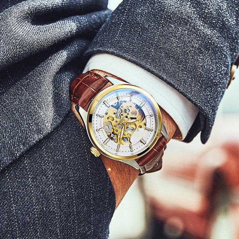 Luxury skeleton watch with gold accents and brown leather strap on a suited wrist