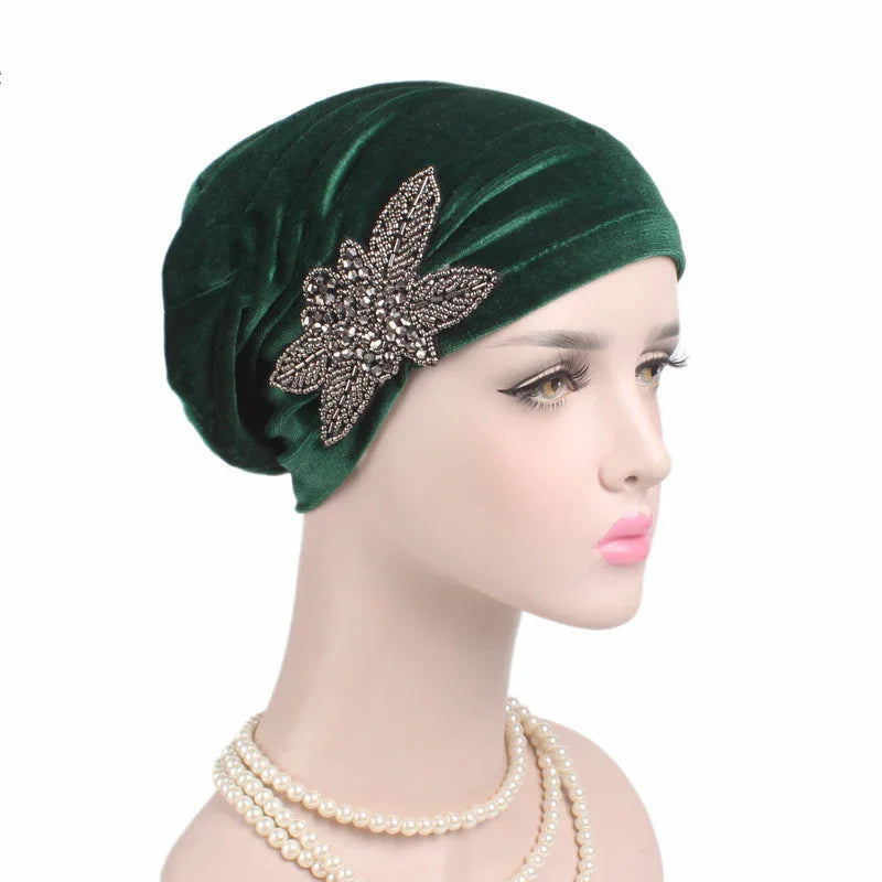 Mannequin wearing dark green velvet turban with beaded floral brooch and layered pearl necklace