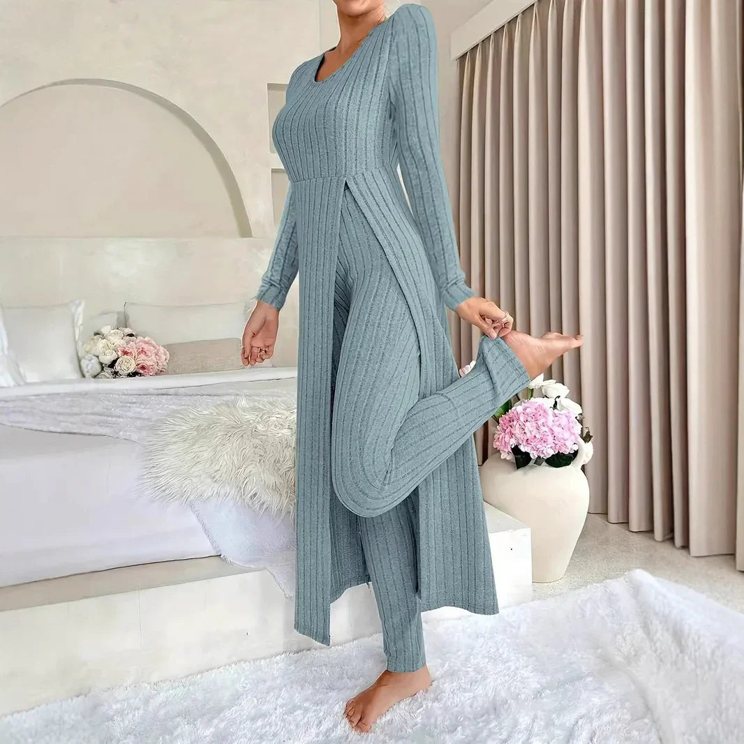 woman wearing light blue ribbed long cardigan and matching pants posing indoors near bed and flowers