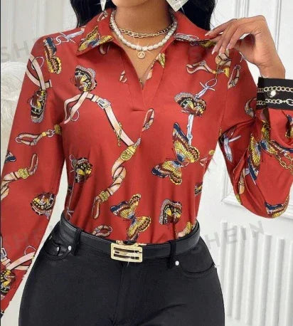 Woman wearing a red patterned blouse with chain and scarf print tucked into high waist black pants with gold belt buckle
