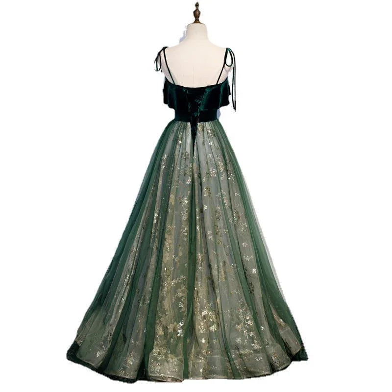 Back view of elegant green evening gown with velvet bodice, spaghetti straps, and floral embroidered tulle skirt