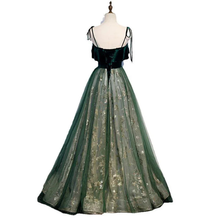 Back view of elegant green evening gown with velvet bodice, spaghetti straps, and floral embroidered tulle skirt
