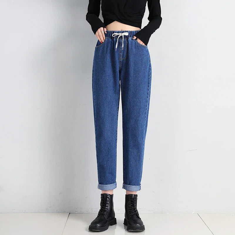 Woman wearing blue high-waisted denim jogger pants with drawstring and black boots