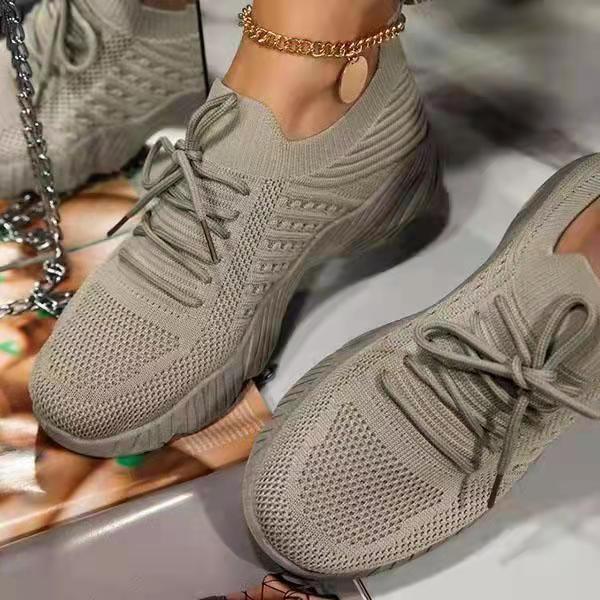 Light gray knitted sneakers with detailed texture and laces, worn with gold anklet on foot