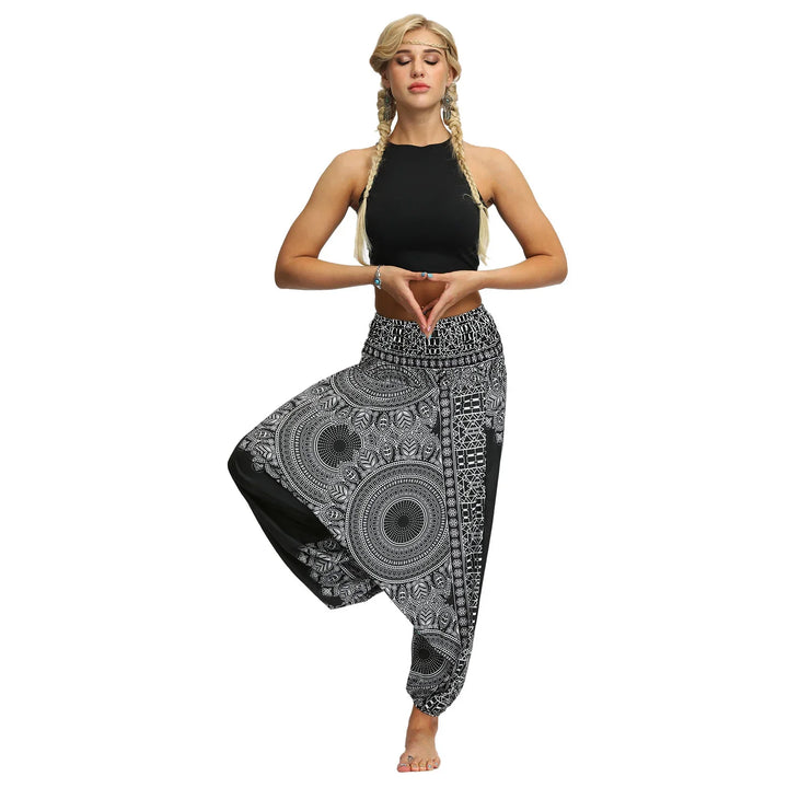 Woman in black crop top and black white mandala print yoga pants performing tree pose