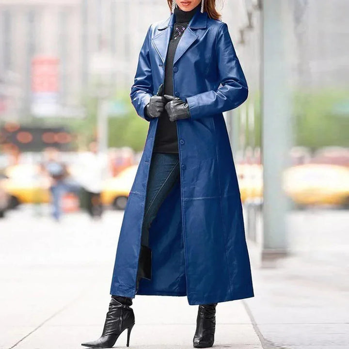 Woman wearing long blue leather coat, black gloves, black turtleneck, jeans, and black heeled boots in city street