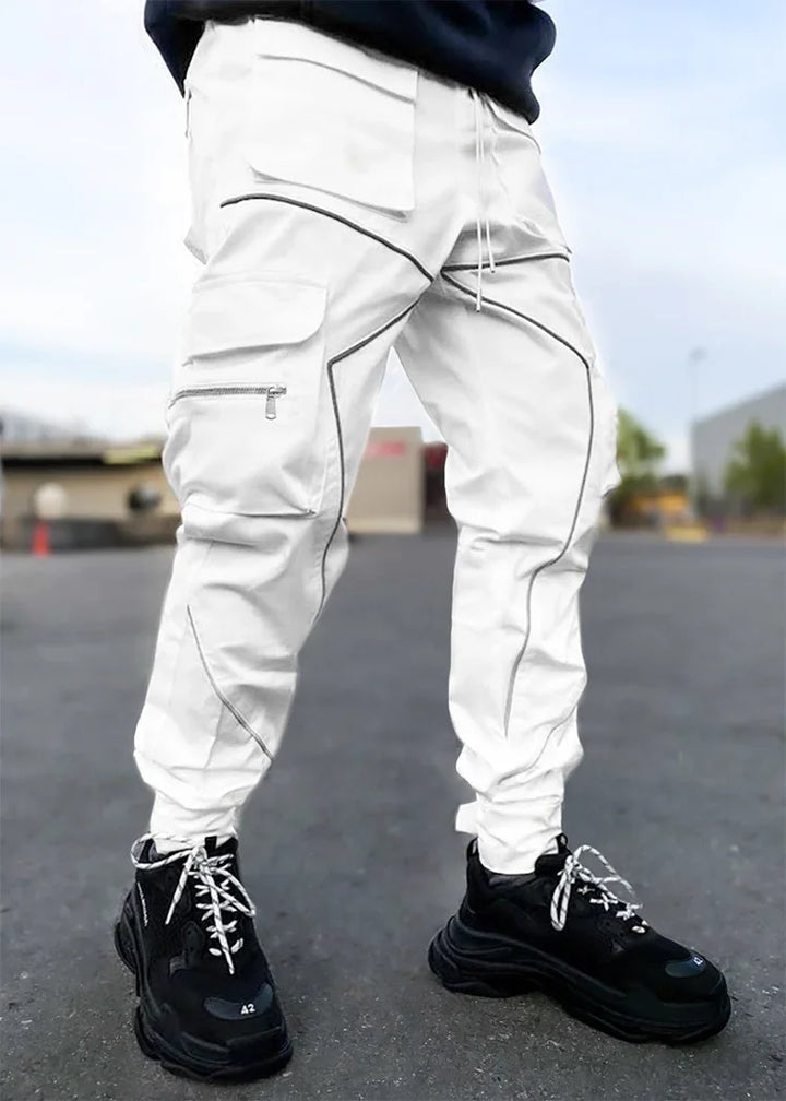 White cargo pants with black accent stitching and zipper pocket worn with black sneakers outdoors