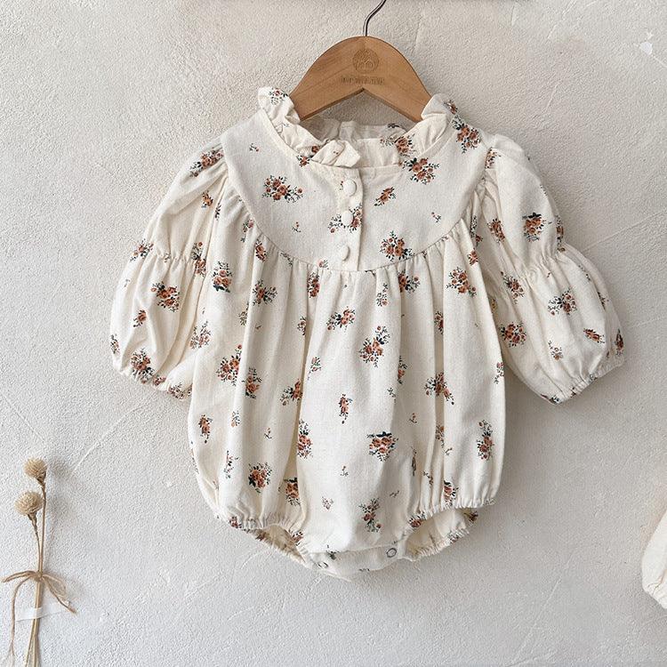 Cream baby romper with brown floral print, puff sleeves, ruffled collar, and snap buttons