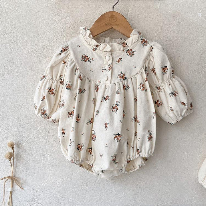 Cream baby romper with brown floral print, puff sleeves, ruffled collar, and snap buttons