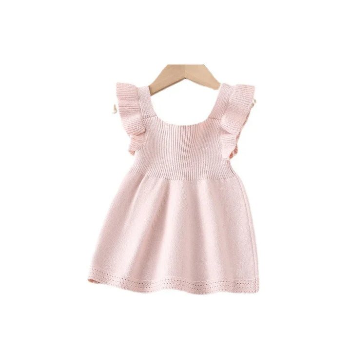 Soft pink knitted baby dress with ruffle sleeves hanging on wooden hanger