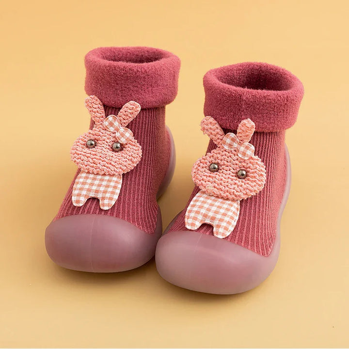 Pink toddler shoes with ribbed knit fabric and cute bunny applique on beige background
