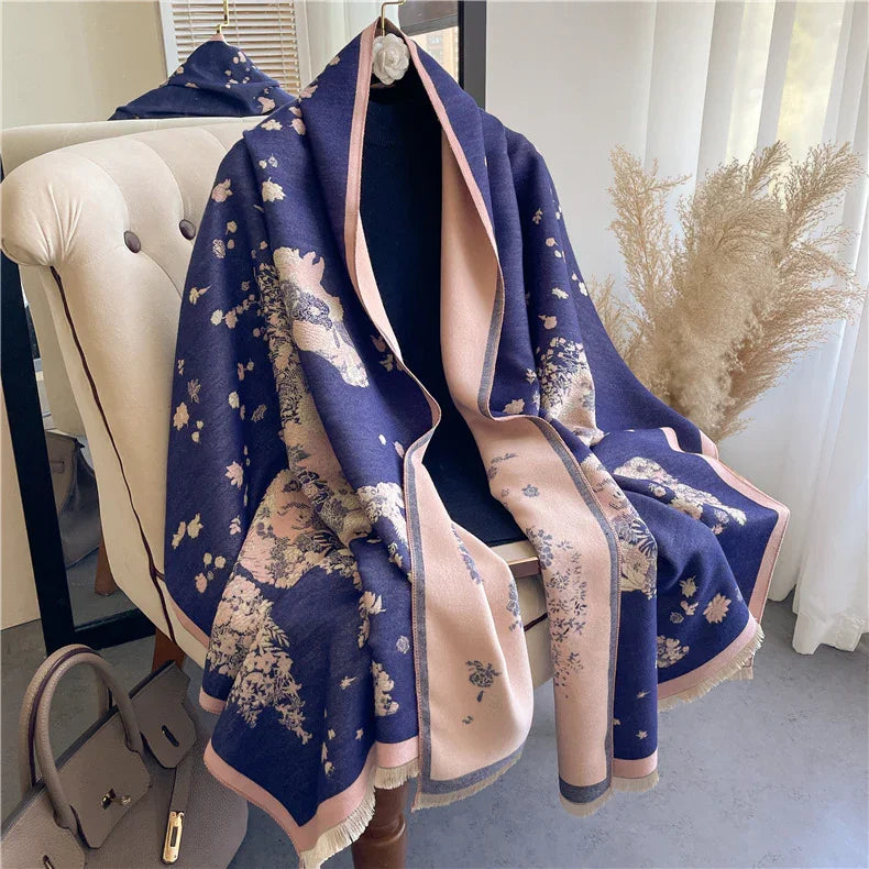 Soft navy and beige floral patterned shawl draped over beige tufted armchair near pampas grass