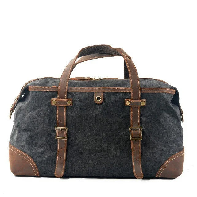 black canvas travel duffel bag with brown leather straps and handles on white background