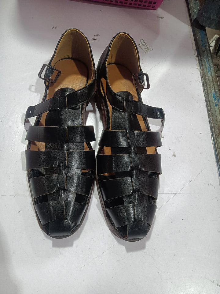Pair of black leather woven sandals with buckles on white surface