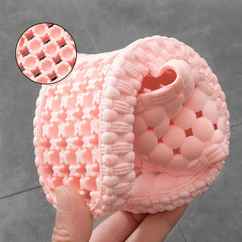 Hand holding flexible pink silicone bath scrubber with textured bubble and grid pattern