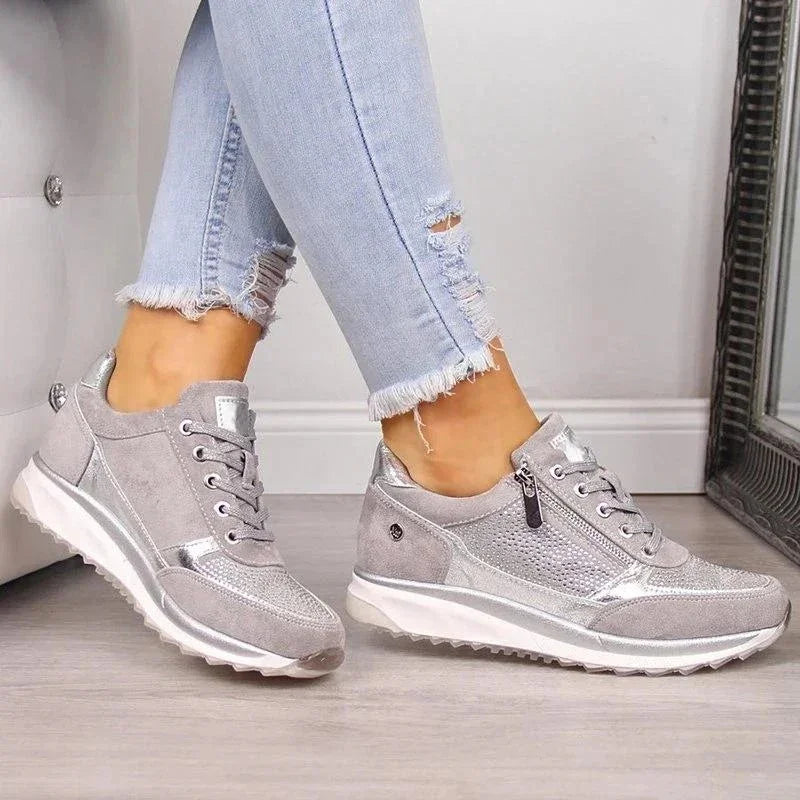 Silver grey stylish women's sneakers with zippers and laces worn with light blue ripped jeans