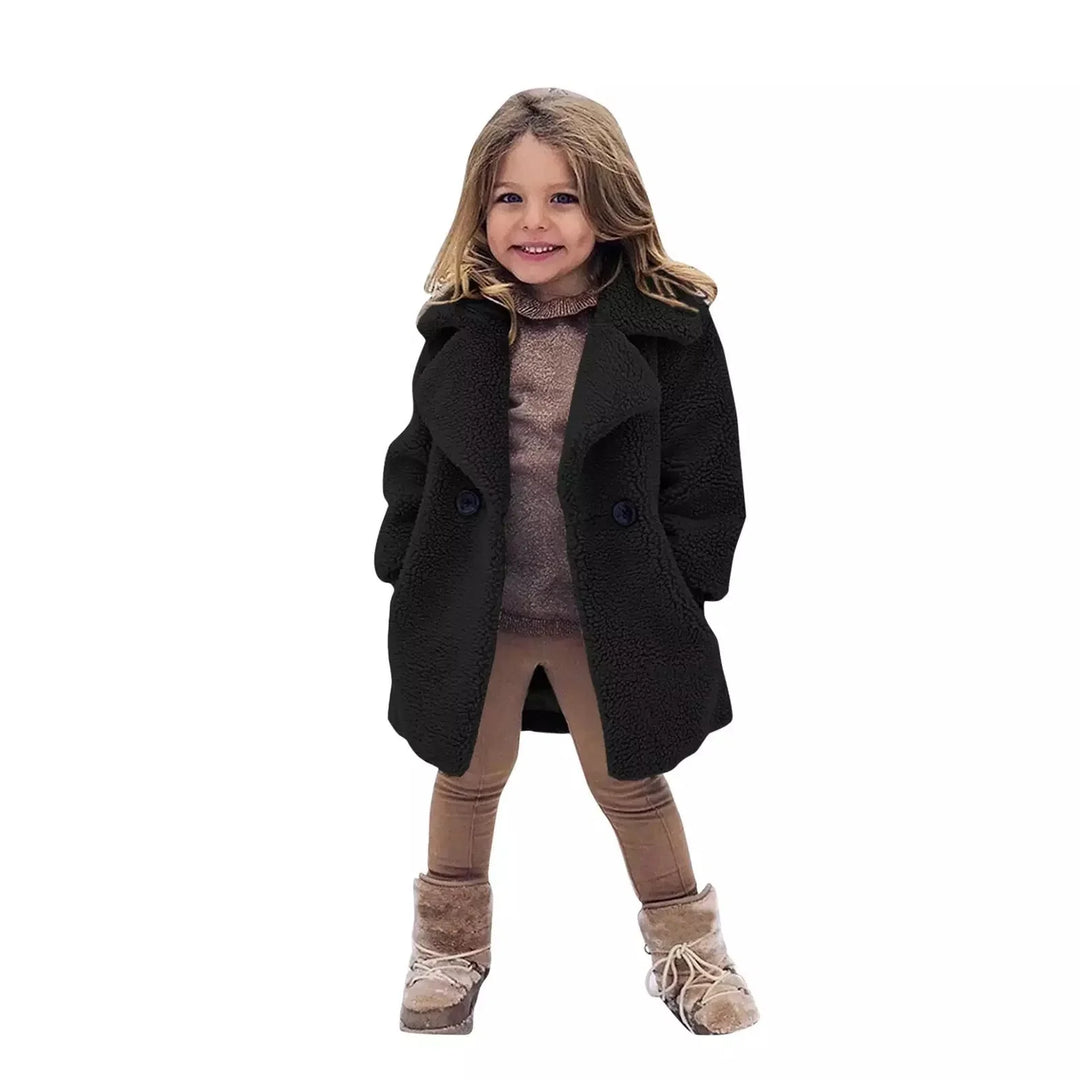 Smiling girl wearing black teddy coat, brown leggings, and beige winter boots
