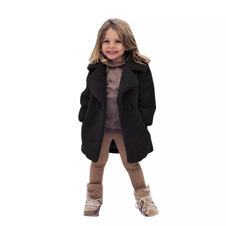 Smiling girl wearing black teddy coat, brown leggings, and beige winter boots