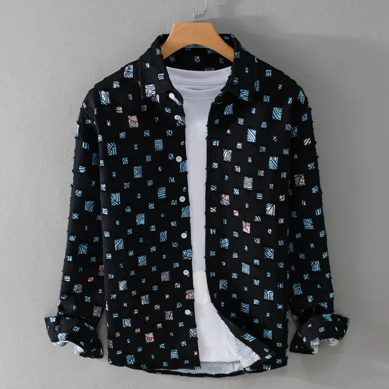 Black button-up shirt with blue and pink geometric patterns over white t-shirt on wooden hanger
