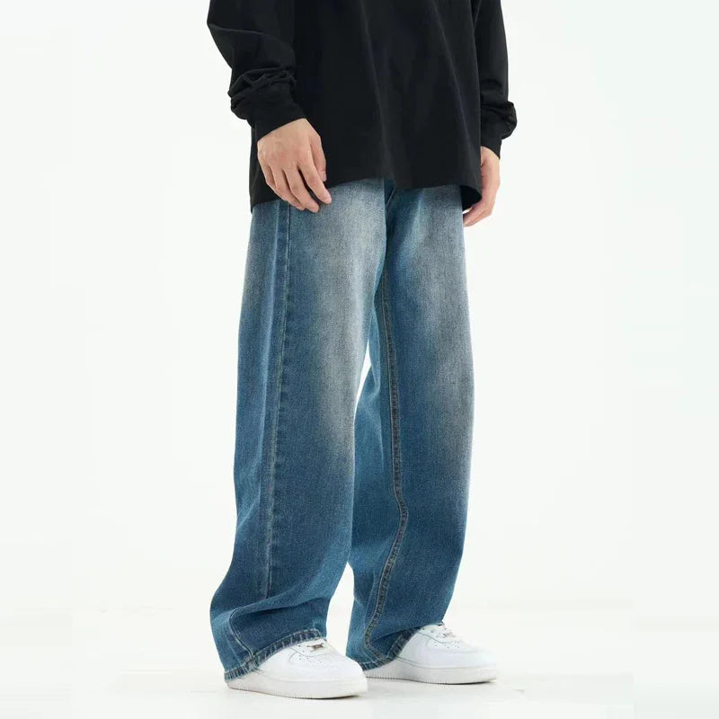 Person wearing baggy blue jeans and white sneakers with a black long sleeve shirt on a white background