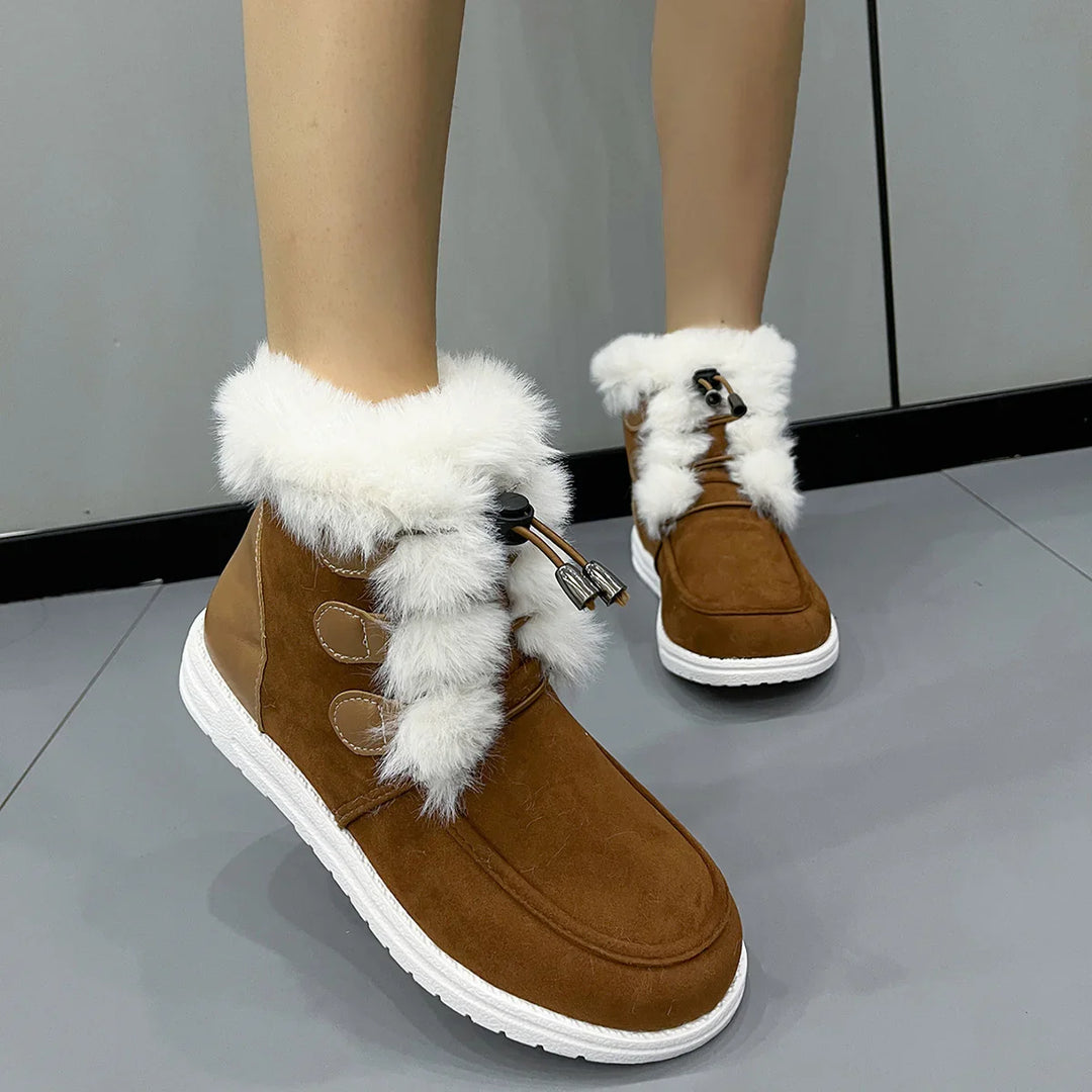 Brown suede winter boots with white fur trim and white rubber soles on gray tiled floor