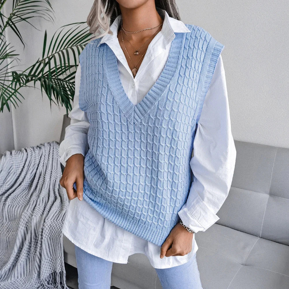 Woman wearing a light blue knitted sleeveless vest over a white button-up shirt in a modern living room