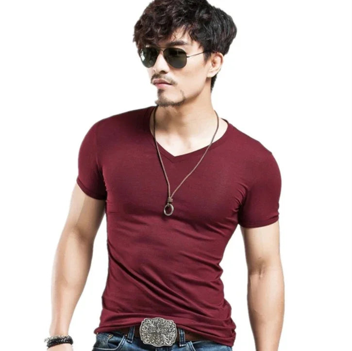 Man wearing maroon V-neck T-shirt, sunglasses, pendant necklace, and decorative belt buckle