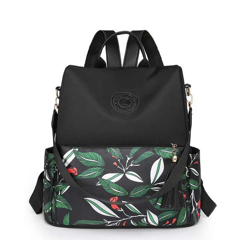 Black backpack with leafy green and red floral pattern, front pocket, and adjustable straps