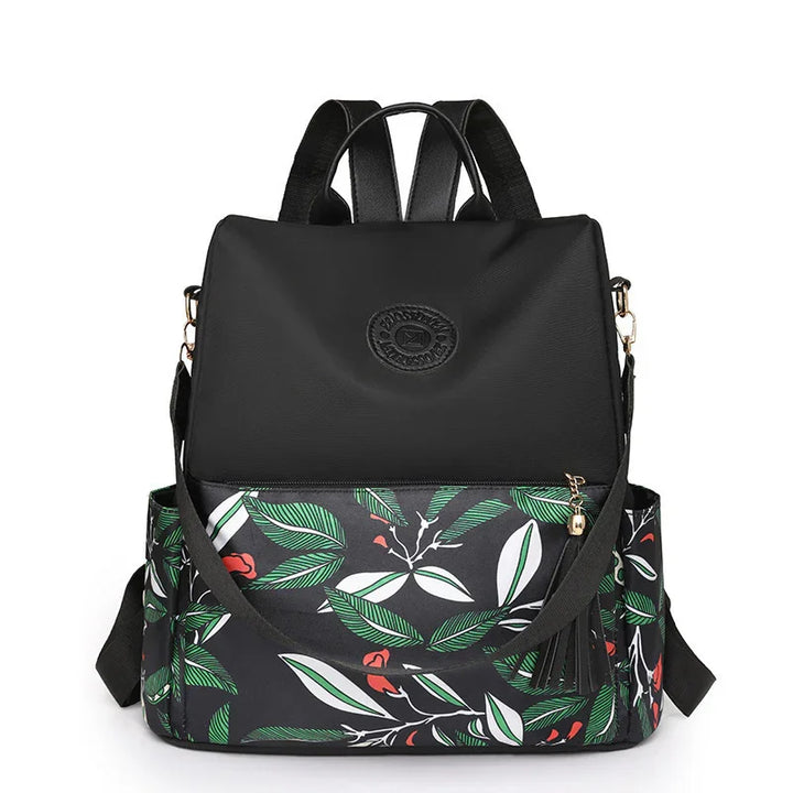 Black backpack with leafy green and red floral pattern, front pocket, and adjustable straps