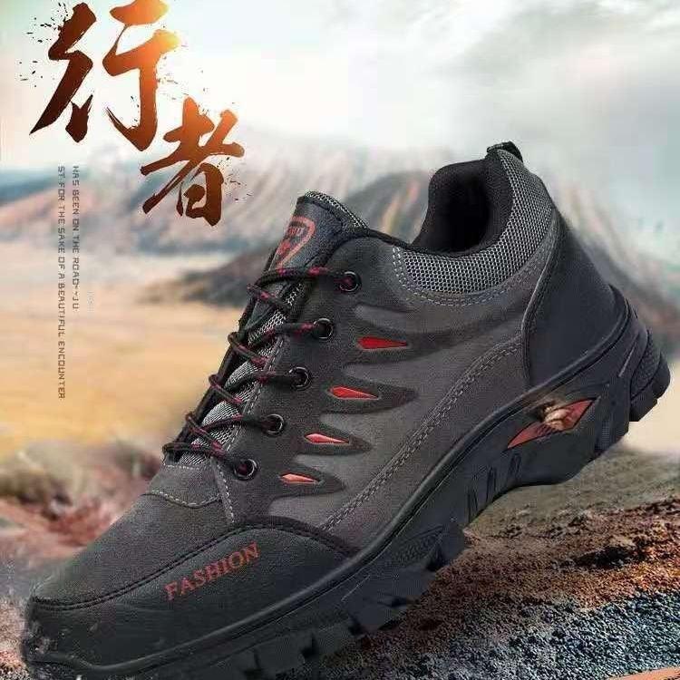 black and gray rugged outdoor hiking shoe with red accents on rocky terrain