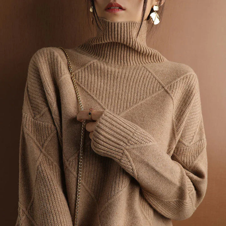 Close-up of a woman wearing a beige turtleneck knit sweater with geometric patterns and gold earrings