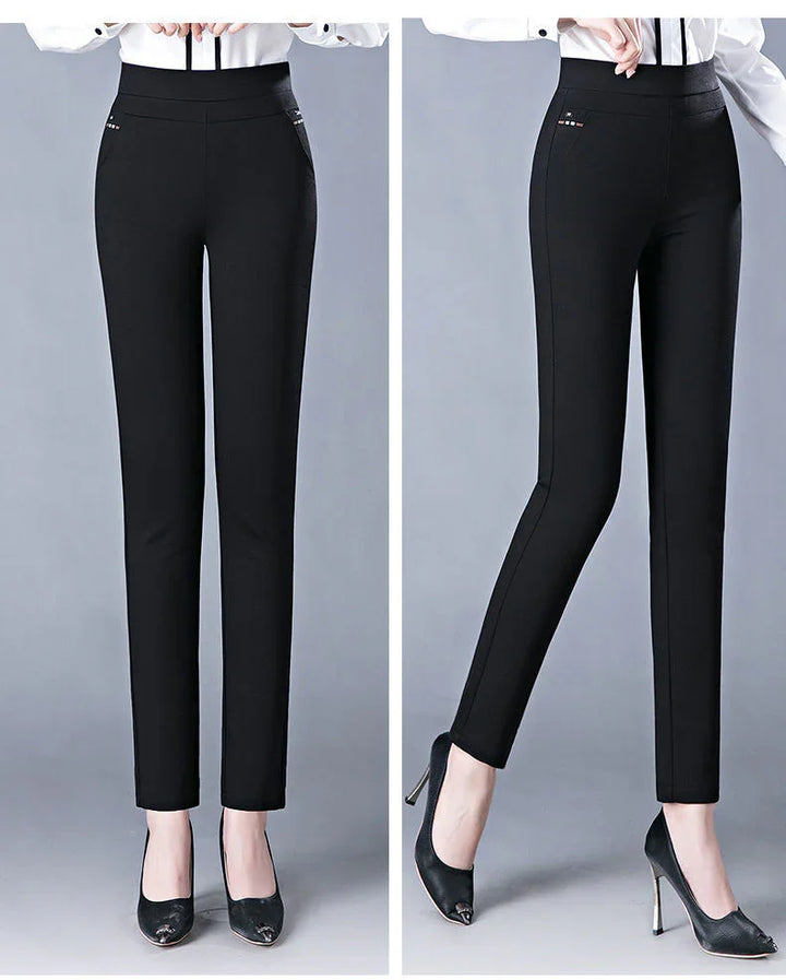 Slim fit black high waist women's dress pants paired with black high heels on gray background