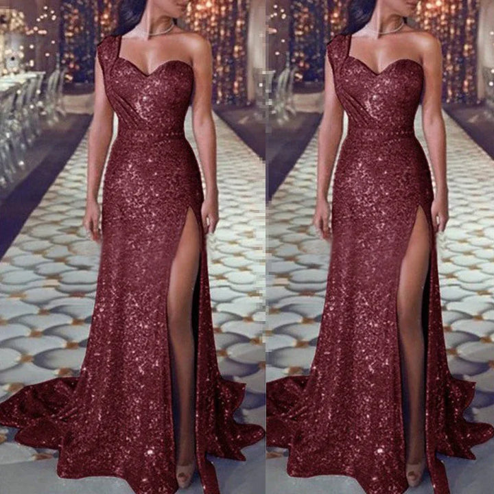 Woman wearing a sparkling burgundy one-shoulder evening gown with thigh-high slit on runway