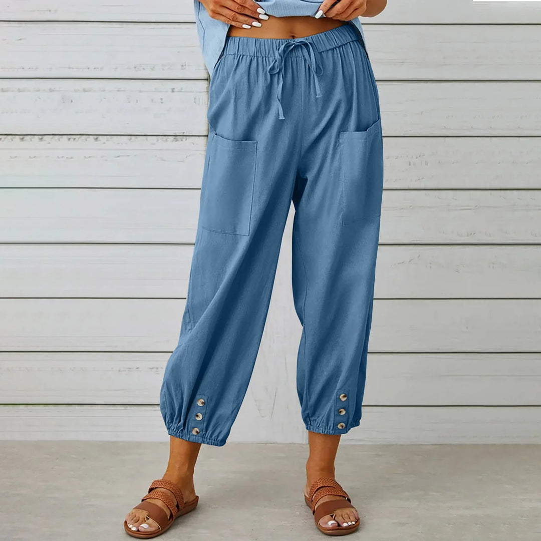 Woman wearing casual blue jogger pants with drawstring waist, front pockets, and button details at ankles
